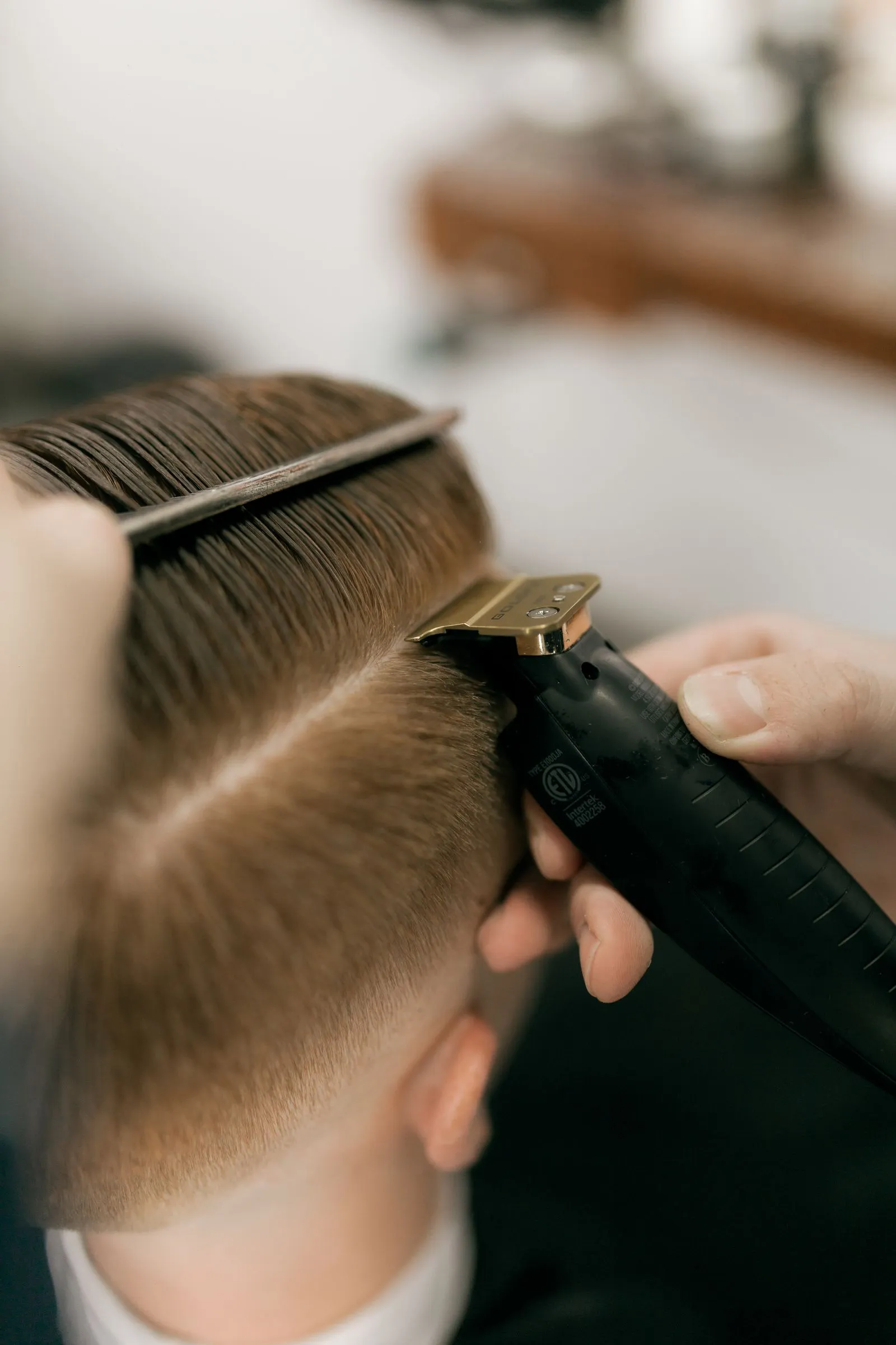 Maquinas de barbería doradas con peina sobre superficie clara