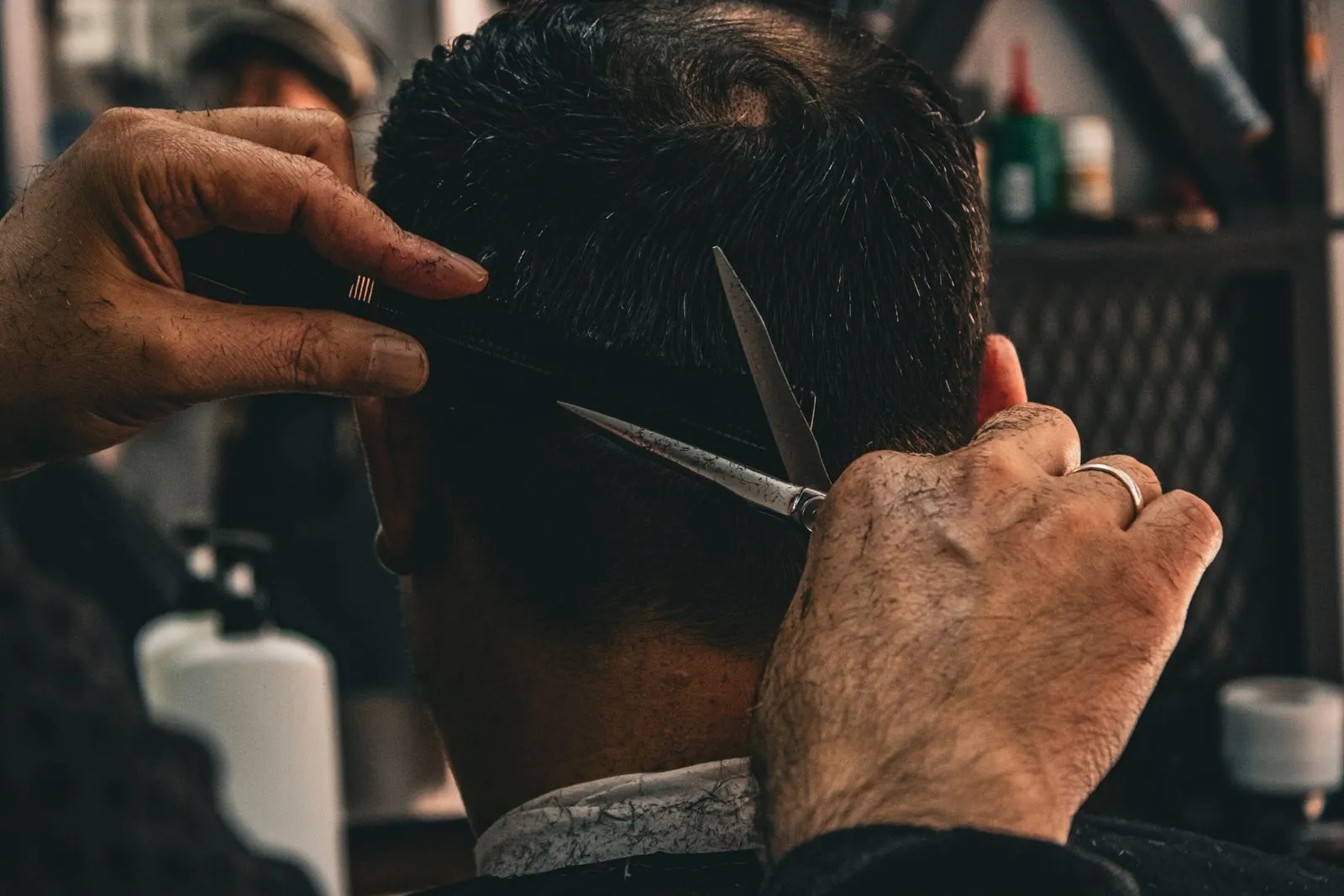 Barber perfilando la parte trasera de la cabeza con tijera