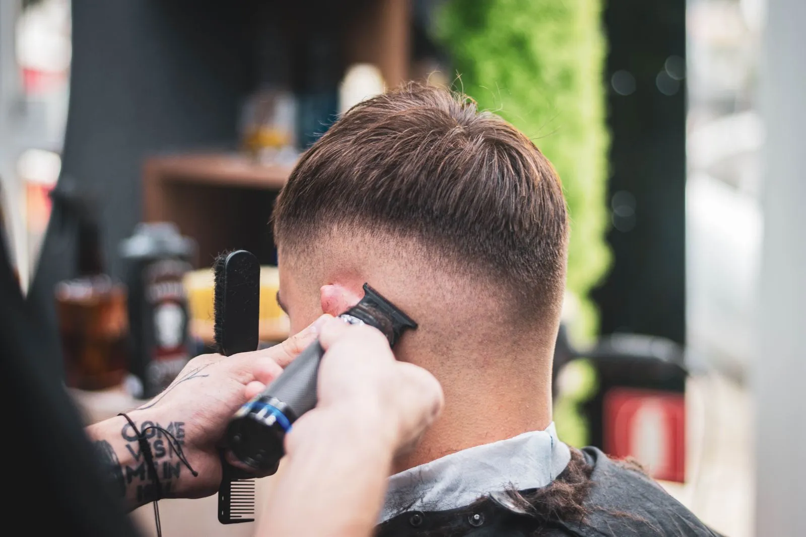 Barber trabajando un fade con máquina en la parte trasera de la cabeza