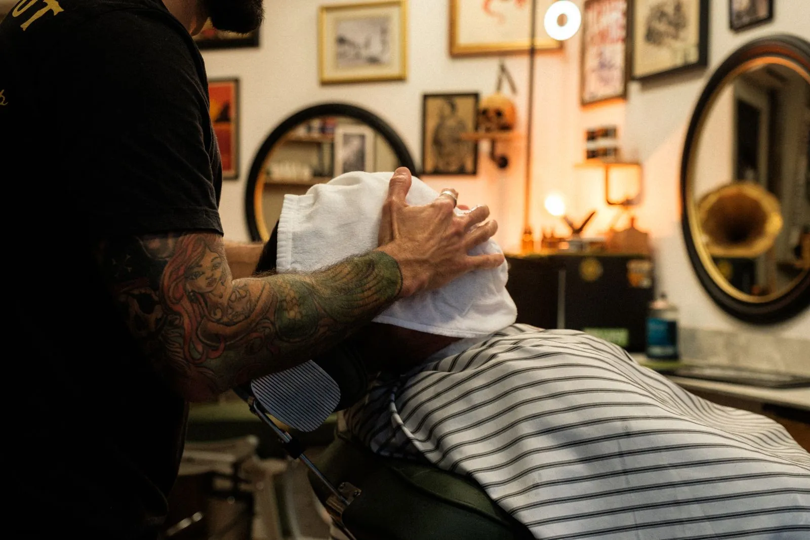 Barber colocando una toalla caliente sobre el rostro de un cliente reclinado